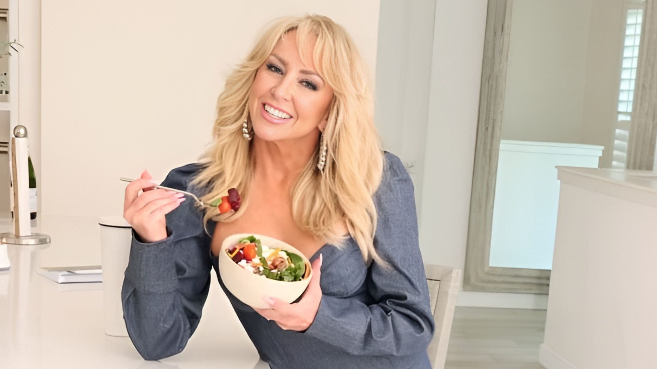 Chalene Johnson smiling, holding a meal in a well-lit kitchen
