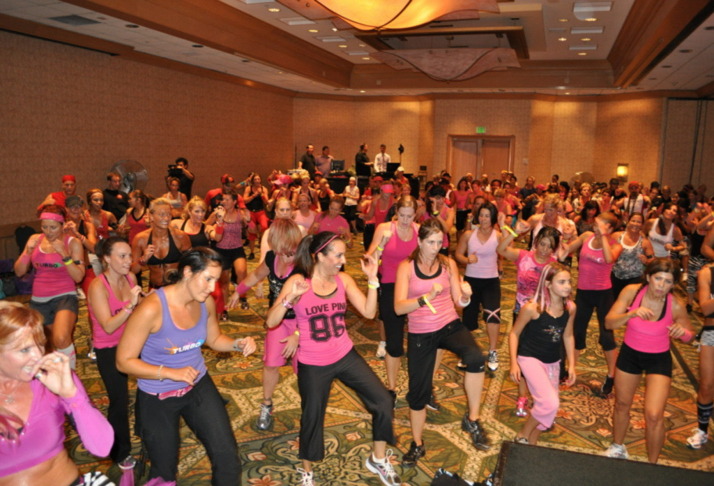 Chalene Johnson leading a Turbo Jam group fitness class with hundreds of women in pink
