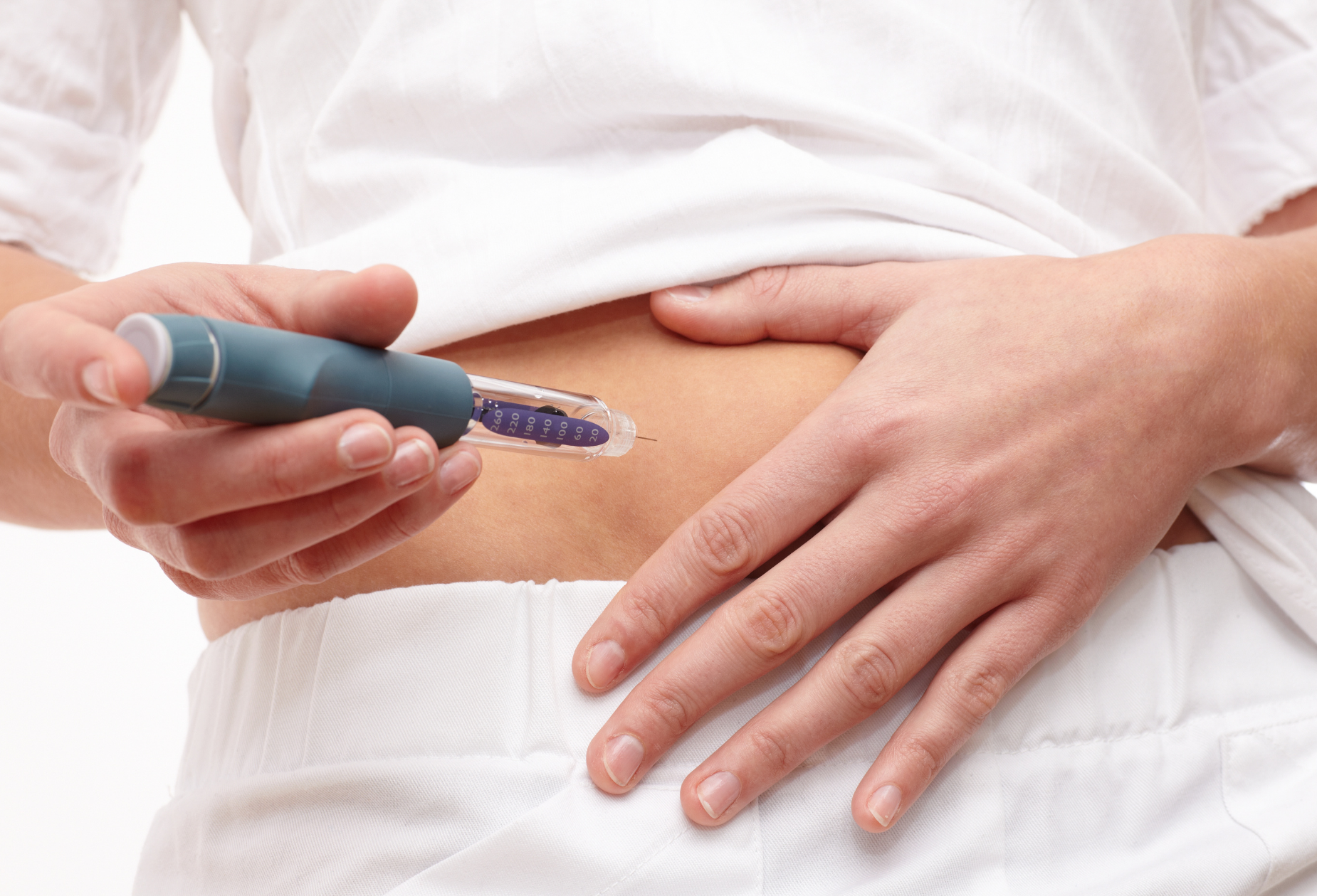 Person administering a GLP-1 weight loss injection in the abdomen, highlighting concerns about muscle loss and body composition changes during rapid weight loss.