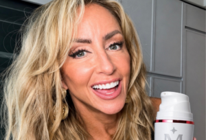 Chalene Johnson smiling while holding her Midi Health estrogen face cream, the topical estrogen treatment she uses for menopausal skin aging