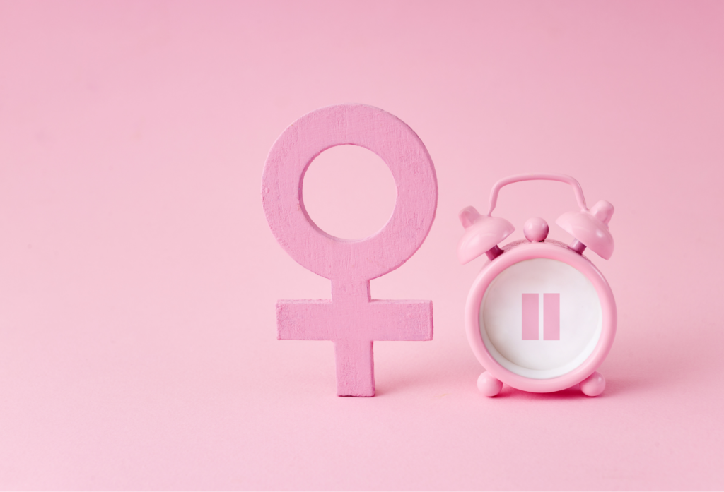 Pink female symbol beside an alarm clock representing the importance of timing when starting hormone replacement therapy during menopause.